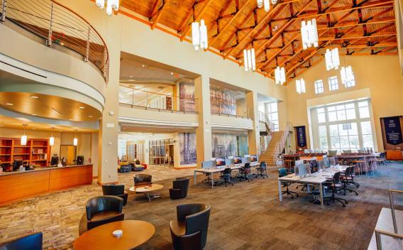 Image shows the main commons area of the Oxford College Library including the front desk and computer tables.